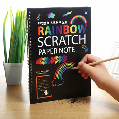 Child scratching a colorful rainbow drawing into the black magic scratch-art paper
