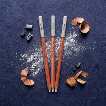 Three Mont Marte white charcoal pencils flatlay on dark surface