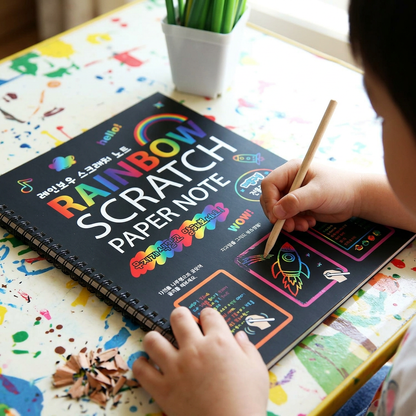 Child scratching a rainbow design into the magic scratch-art book
